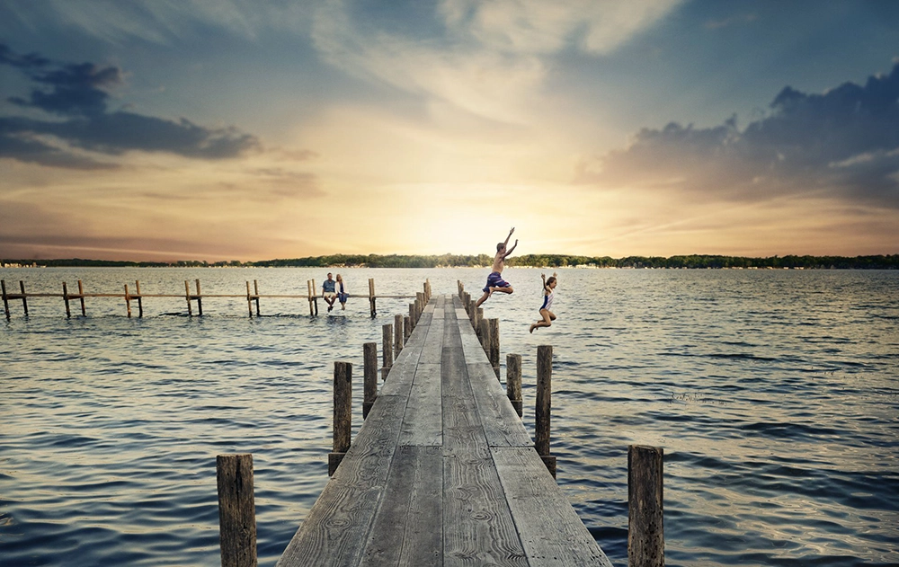 Kids jumping into a lake off the dock